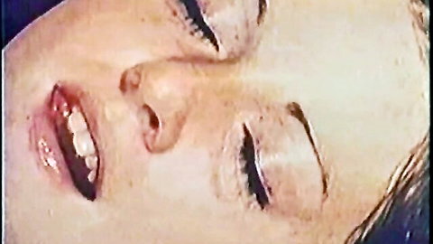 Close-up of blonde woman with glossy lips and closed eyes in 1974 retro porn ecstasy