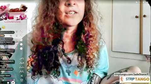 Curly-haired Greek camgirl Mounaros in blue tank top on Strip Tango webcam
