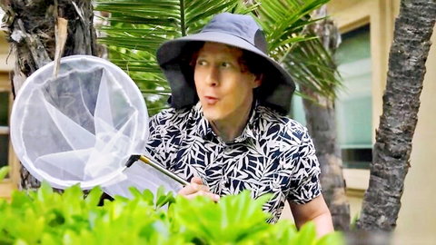 Surprised woman in hat and shirt holds net in lush garden, outdoor adventure vibe