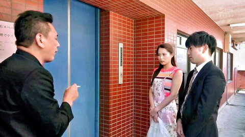 Japanese wife in floral dress with two suited Asian men in hallway scene