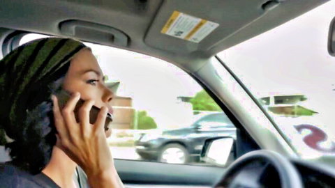 Ebony woman in headwrap talks passionately on phone in car, softcore fetish vibe