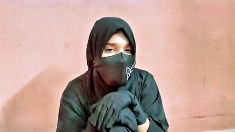Veiled Muslim woman in black hijab, niqab and gloves posing intimately