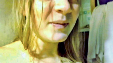 Mature blonde woman moans with parted lips and tongue tip out in webcam tease