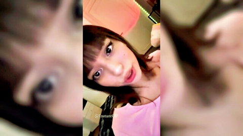 Sexy Asian woman with bangs in pink top, close-up selfie