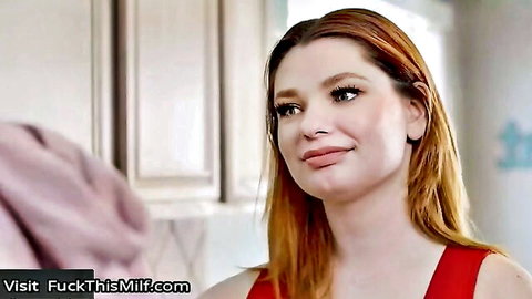 Seductive redhead MILF with huge tits smirks in tight red dress showing deep cleavage