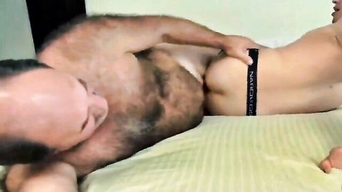 Hairy older daddy groping smooth young twink's bare ass cheeks on bed in gay amateur action