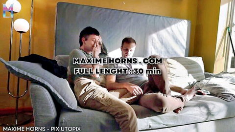 Three men in casual clothes sit intimately on couch, one covering eyes while others touch playfully