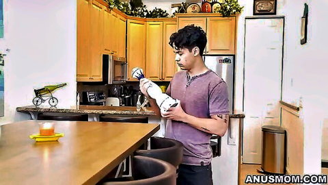 Curly-haired guy in purple shirt holds white bottle in modern kitchen on AnusMom