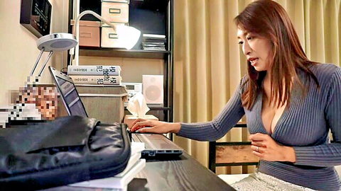 Reiko Kobayakawa mature Japanese woman in low-cut gray sweater showing cleavage at desk