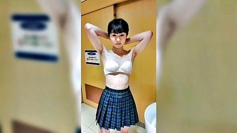Petite Japanese girl in white lace bra and navy school skirt posing with arms raised