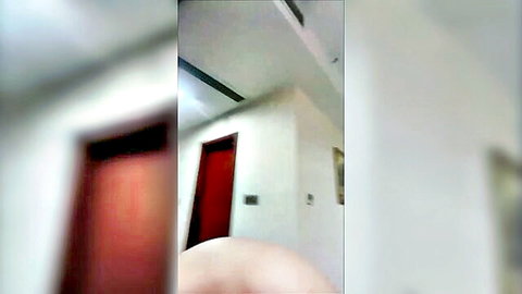 Blurry empty hallway with red door white walls and foreground finger.