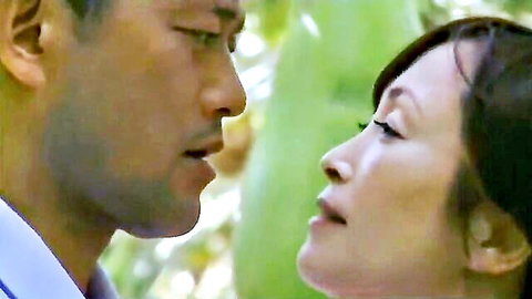 Handsome Japanese man and sexy Asian woman gaze intimately close-up outdoors among greenery