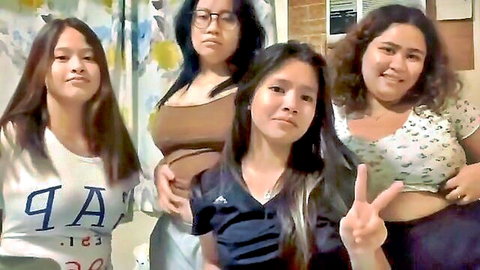 Four cute Filipina girls in tight tops posing with peace signs in bathroom