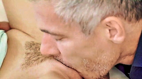 Gray-haired mature man sucking woman's nipple passionately closeup