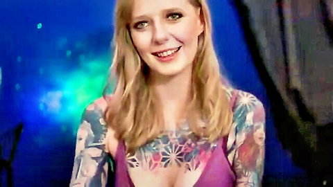 Tattooed blonde MILF smiling with deep cleavage in tight purple top