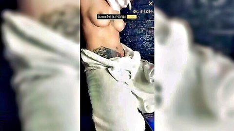 Tattooed Asian woman topless in towel, exposing breasts in steamy bathroom