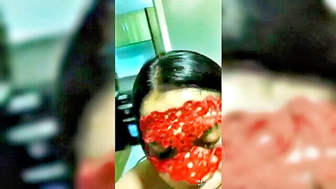 Blurry homemade closeup of Southeast Asian woman with red-smeared face mask and black hair