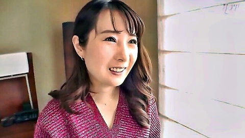 Cute smiling Asian woman in pink V-neck sweater teasing in hotel room