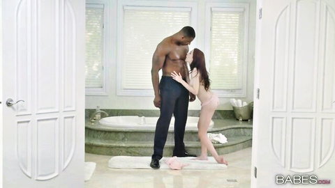 Petite redhead nude embracing muscular black man in intimate bathroom pose