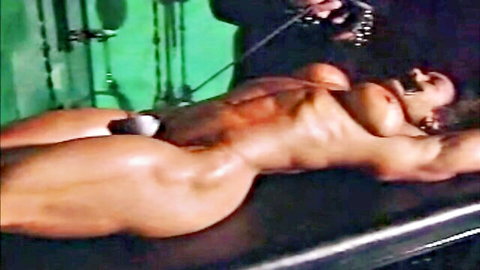Muscular tanned big tits woman bound naked on table with chains exposing pussy in BDSM slave play