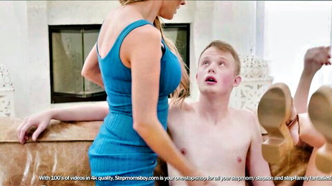 Blonde MILF in tight blue dress gropes naked freckled young guy's bare chest on couch