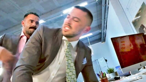 Suited muscular man roughly grabs coworker from behind in intense gay office roleplay