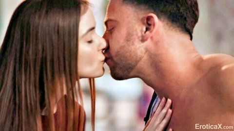 Brunette with long hair passionately kissing muscular bearded shirtless hunk