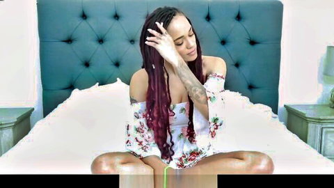 Tattooed ebony babe with maroon dreads teasing crotch in floral off-shoulder top on bed