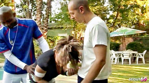 Blonde slut kneels sucking white guy's thick cock outdoors as black stud in jersey watches poolside