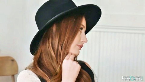 Seductive redhead babe in black hat and lace top posing teasingly with wet lips