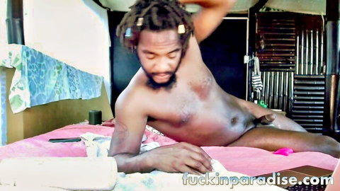 Muscular dreadlocked black stud lies nude on pink bed spreading legs to expose huge erect BBC and balls