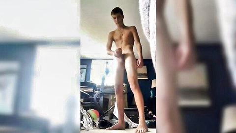 Slim young white man nude, holding erect penis in solo pose