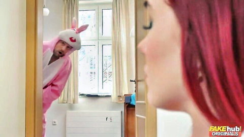 Man in pink bunny costume stares at pink-haired babe's reflection in bedroom mirror