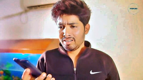 Surprised Indian guy in Nike jacket holding phone looking shocked