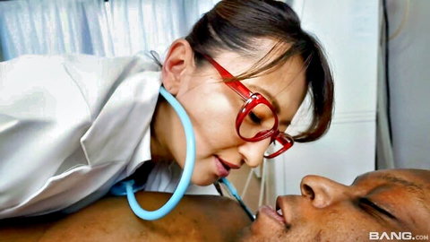 Asian nurse with red glasses uses stethoscope on black man's bare chest in seductive medical exam