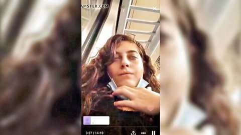 Blurry closeup of curly-haired girl with face mask pulled down on escalator selfie