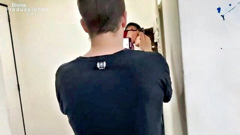 Man in black shirt stands from behind in bathroom mirror selfie for Divina Producciones