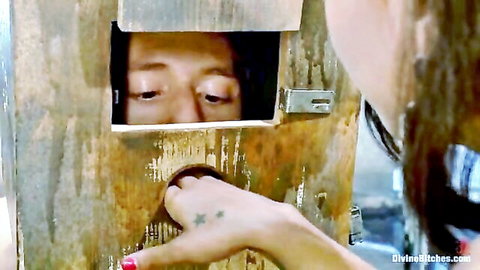 Ebony mistress teases male slave's face in gloryhole setup with tattooed hand