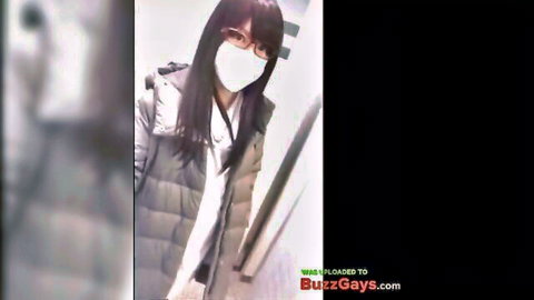 Chinese crossdresser in green jacket, mask, and glasses seductively posed