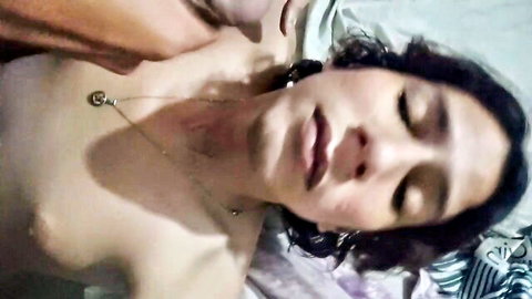 Close-up of seductive femboy lying topless with eyes closed, necklace