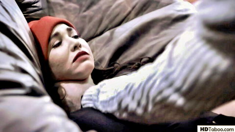 Angela White lying on couch in red beanie, eyes closed, seductive pose