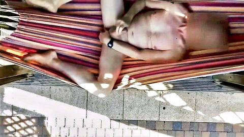 Muscular young guy lying naked on outdoor hammock exposing his big semi-hard cock