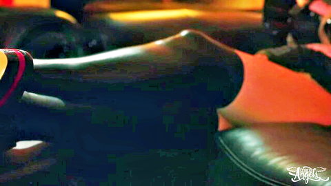 Muscular ebony thighs in sheer black stockings and orange sandals teasing on leather couch