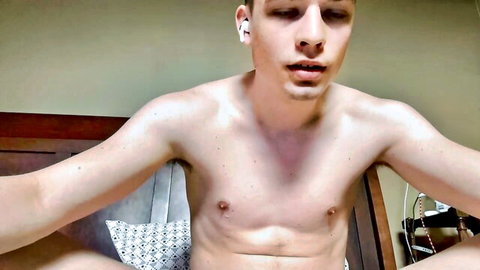 Shirtless twink lounges on bed in underwear showing smooth chest and abs webcam tease