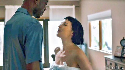 Tall black stud in shirt towers over topless small-tits babe in white towel, intense gaze