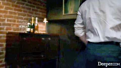 Handsome man in white shirt stands by champagne glasses and candle in romantic brick room setup