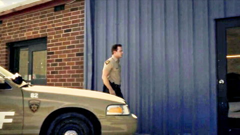 Shelley Hennig as Malia in sheriff uniform, standing by police car from Teen Wolf