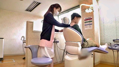 Japanese dental nurse in uniform treating young male patient in clinic chair