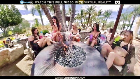Six busty bikini babes lounging seductively around outdoor fire pit in VR