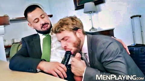 Suited bearded man sucks thick black dildo fed by muscular colleague in intense gay office blowjob.